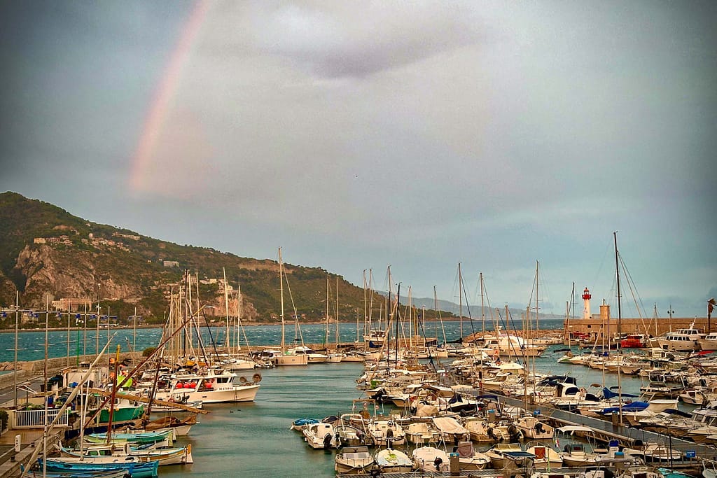 Am Ziel der Route des Grandes Alpes in Menton leuchtet ein Regenbogen über dem Hafen zum Abschied. Foto: Mario Vedder