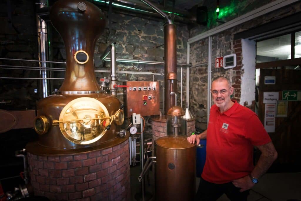 Märkische Spezialitätenbrennerei: Obstbrände retten alte Streuobstsorten im Sauerland 1 Klaus Wurm vor dem Herzstück der Märkischen Spezialitätenbrennerei: Die glänzende Kupferblase, in der alte Obstsorten veredelt werden.. Foto: Mario Vedder
